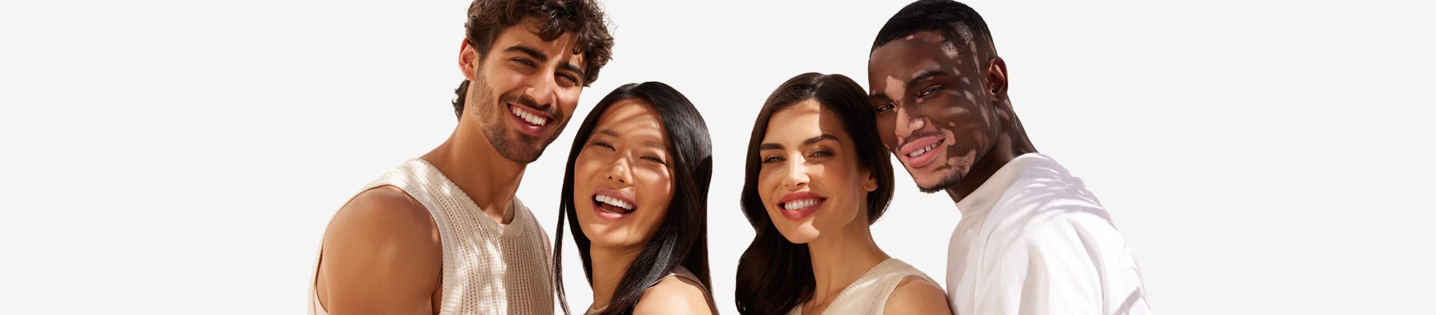 View of four people smiling while embracing each other and looking straight at the camera.