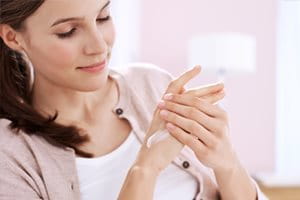 Femme appliquant de la crème sur ses mains.