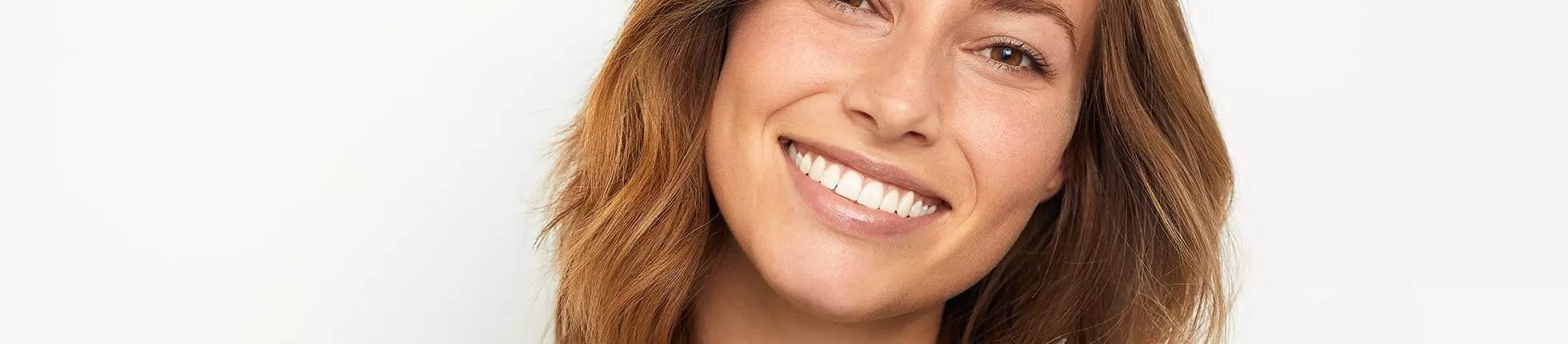 Sourire d'une femme avec des premières rides du visage, exprimant une beauté naturelle et une attitude positive.