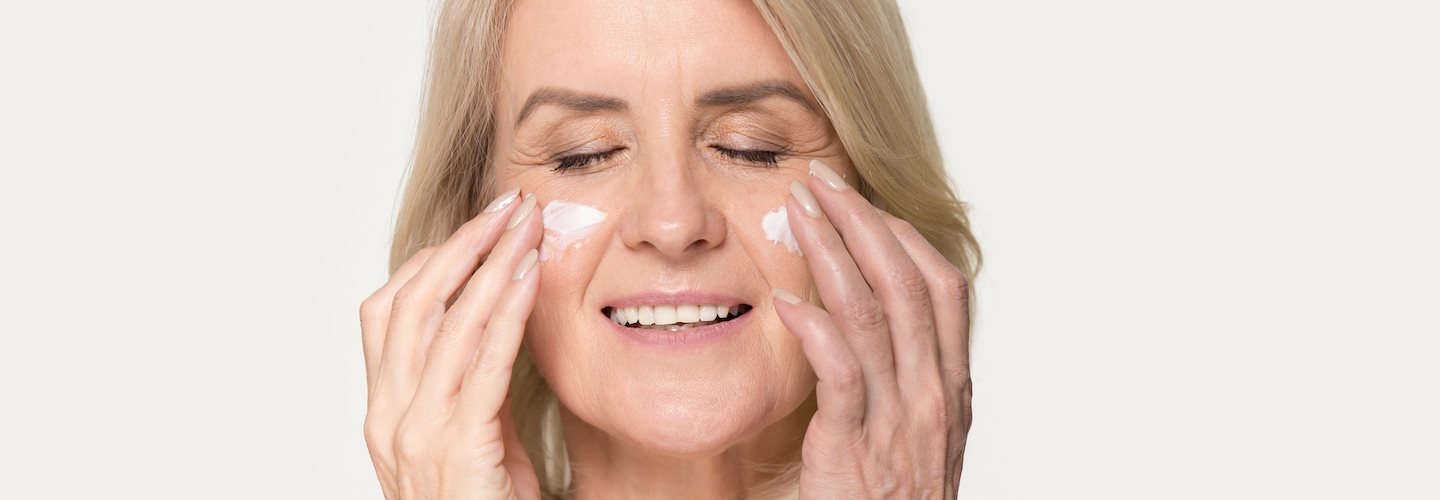 Ältere Frau, die Creme auf ihr Gesicht aufträgt