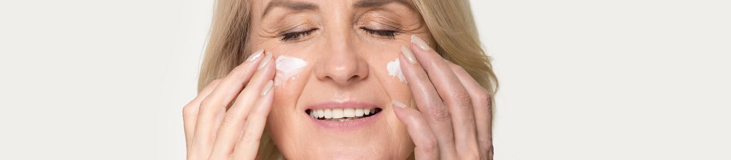 Ältere Frau, die Creme auf ihr Gesicht aufträgt