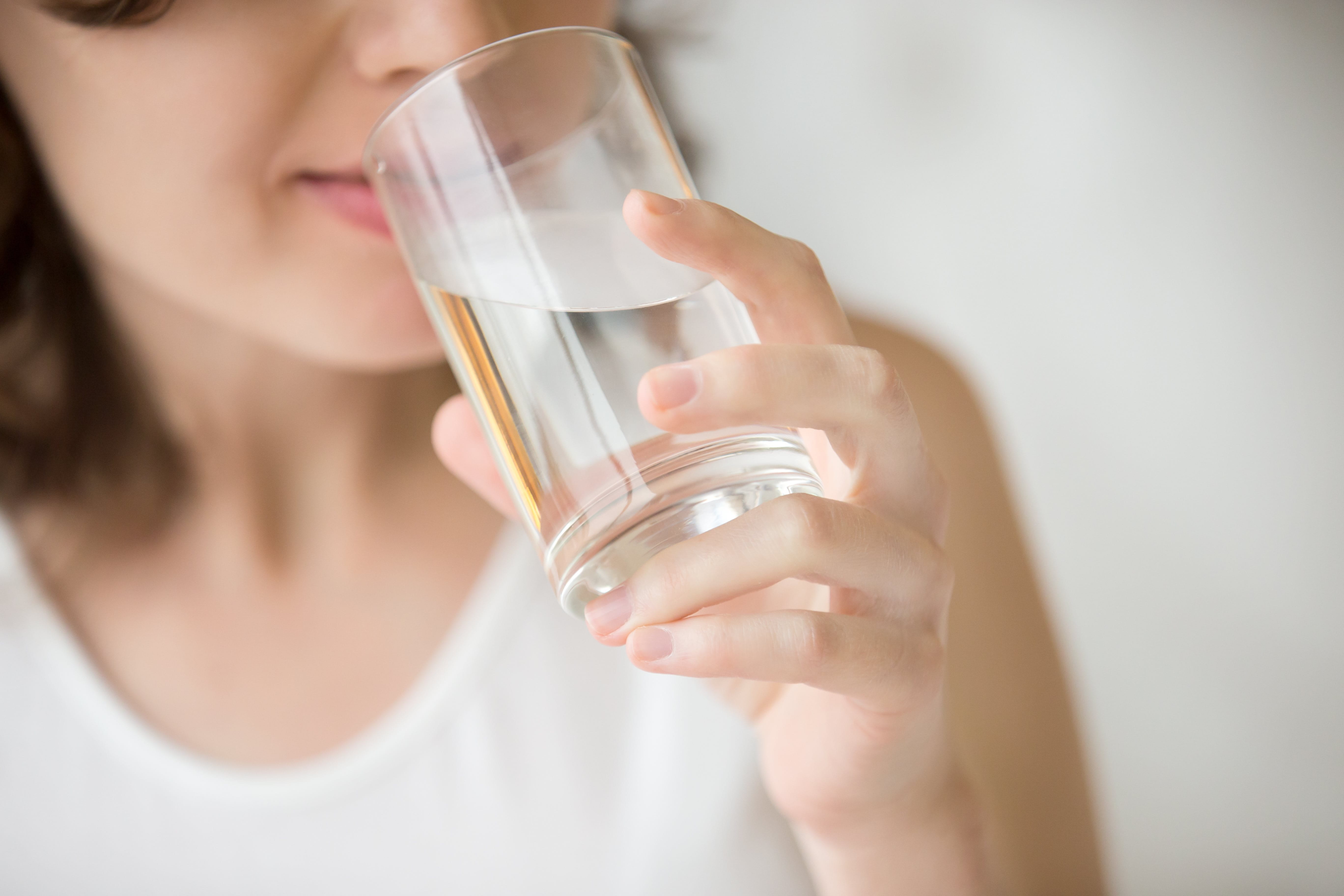 Frau trinkt Wasser aus einem Glas.