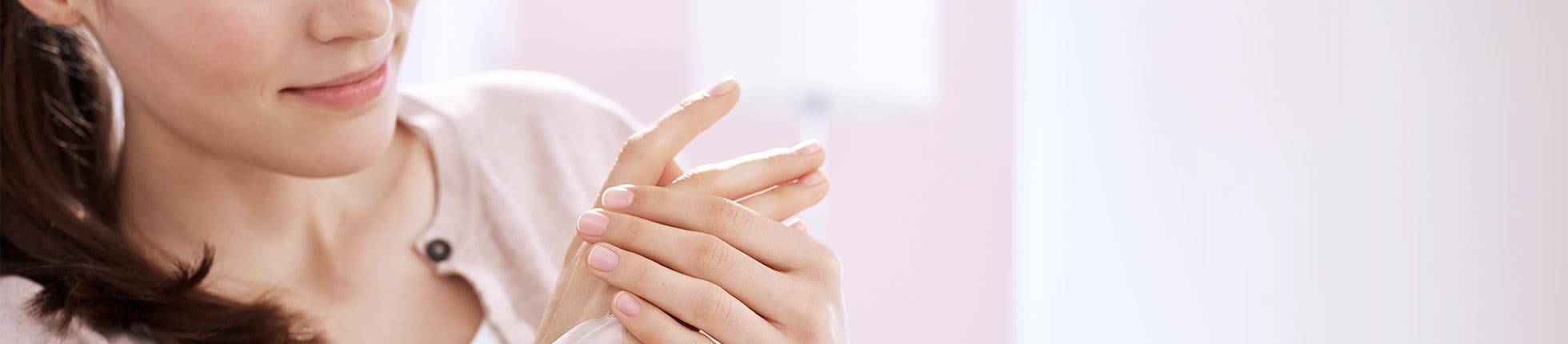 Femme appliquant de la crème sur ses mains.