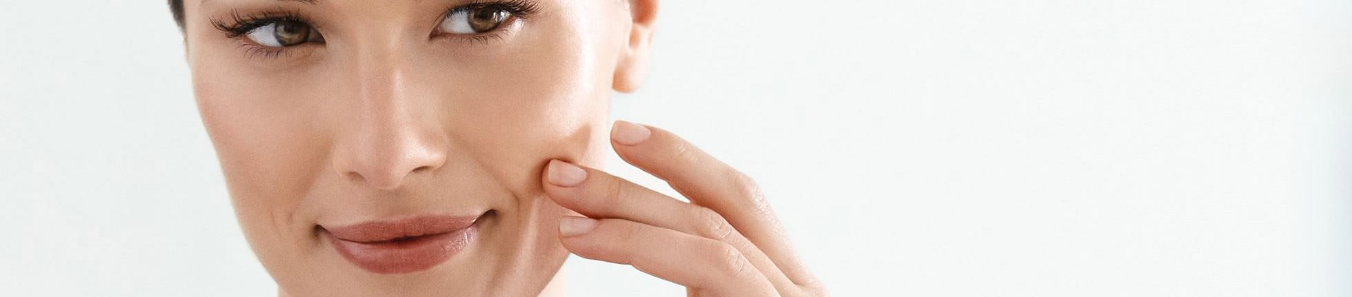 Frau behandelt ihre Nasolabialfalte mit Hyaluron Creme