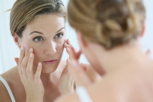 Frau mit perioraler Dermatitis schminkt sich im Spiegel