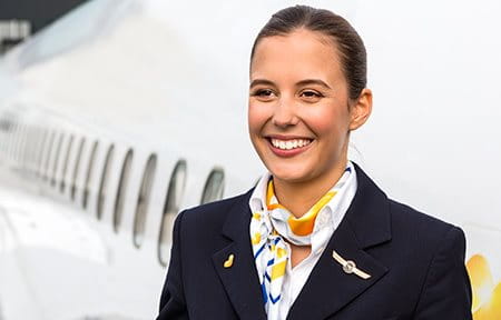 Stewardess lächelnd vor Flugzeug