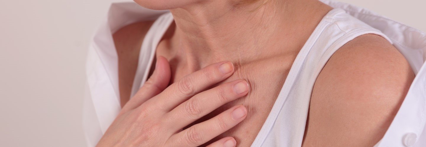 Frau legt eine Hand auf das Dekolleté
