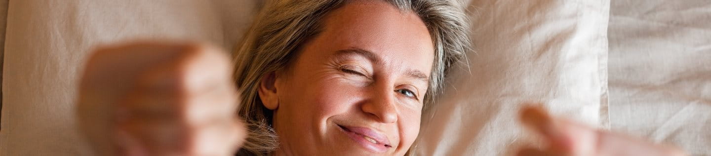 Frau mittleren Alters streckt sich nach dem Schönheitsschlaf