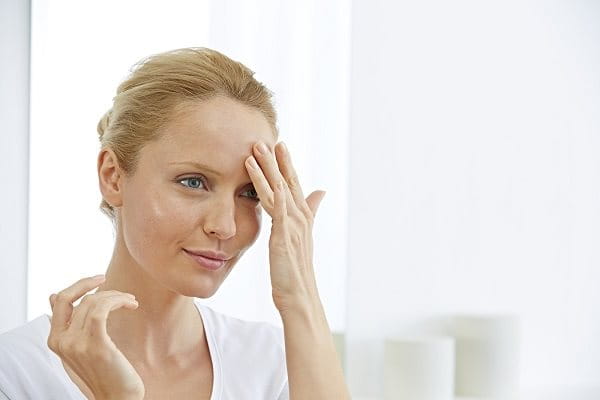 Frau cremt sich Stirn ein gegen Zornesfalte