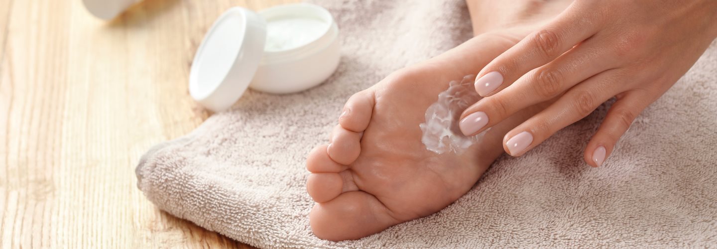 Frau cremt sich die Füße ein