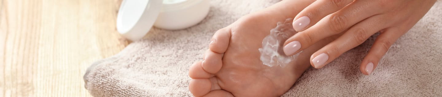 Frau cremt sich die Füße ein