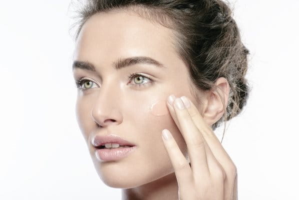 Frau cremt sich das Gesicht mit einer Pflege mit Glycerin ein