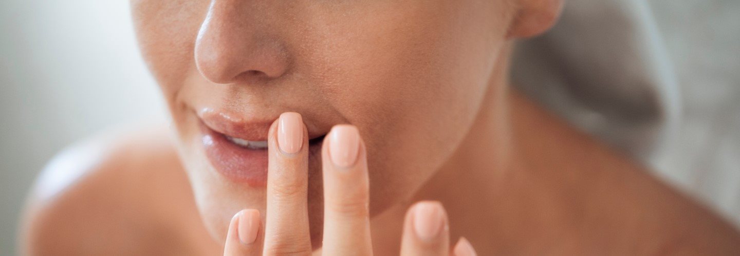 Frau trägt Lippenpflege mit den Fingern auf