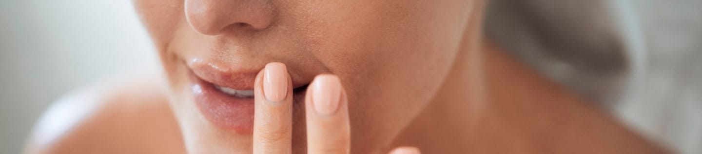 Frau trägt Lippenpflege mit den Fingern auf