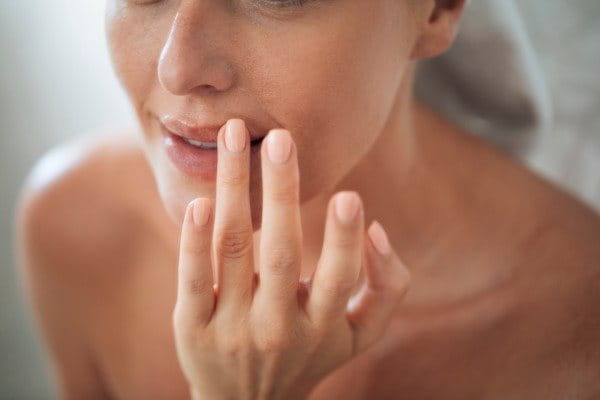 Frau streicht sich mit dem Finger über die Lippe