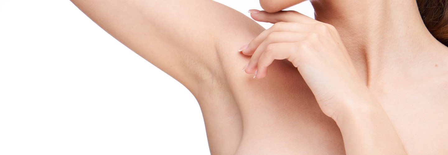  Junge frau schaut auf ihre rechte Achsel, weil sie unter juckenden Achseln leidet. 