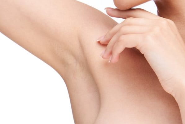 Junge frau schaut auf ihre rechte Achsel, weil sie unter juckenden Achseln leidet.