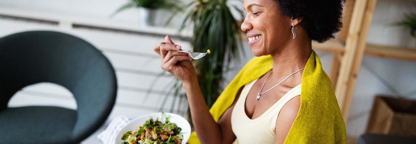 Im Schneidersitz sitzende Frau, die einen gesunden Salat isst