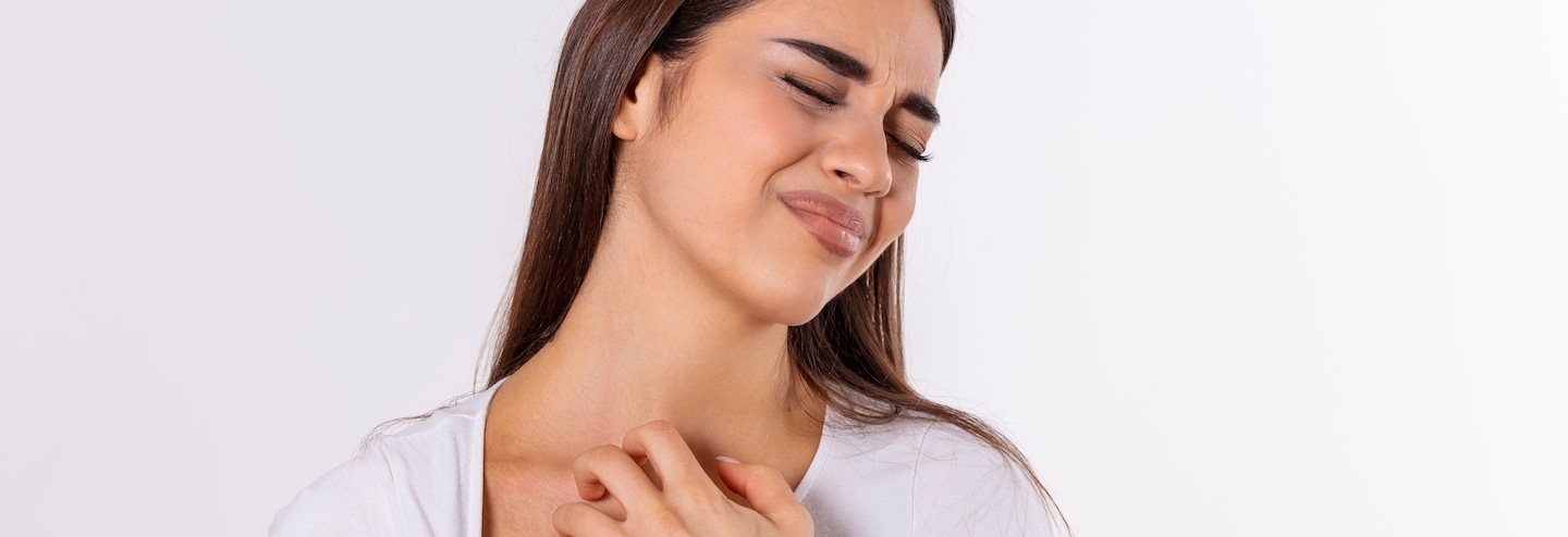 Frau, die sich am Hals kratzt