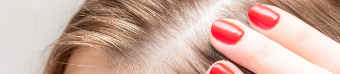 Frau berührt ihren Scheitel.