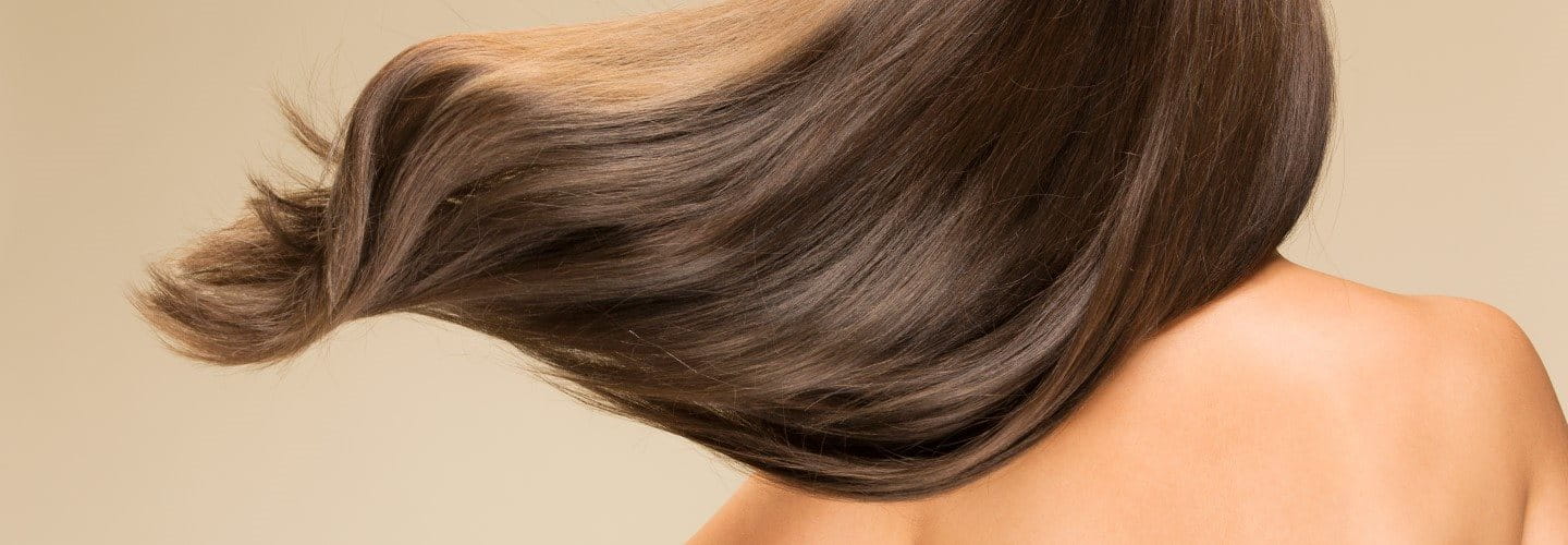 Ansicht einer brünetten Frau mit wallendem gesunden Haar von hinten.