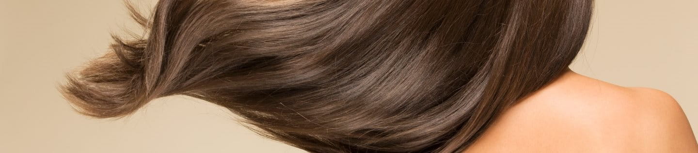 Ansicht einer brünetten Frau mit wallendem gesunden Haar von hinten.