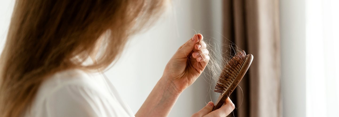 Frau entfernt herausgefallene Haare von einer Haarbürste