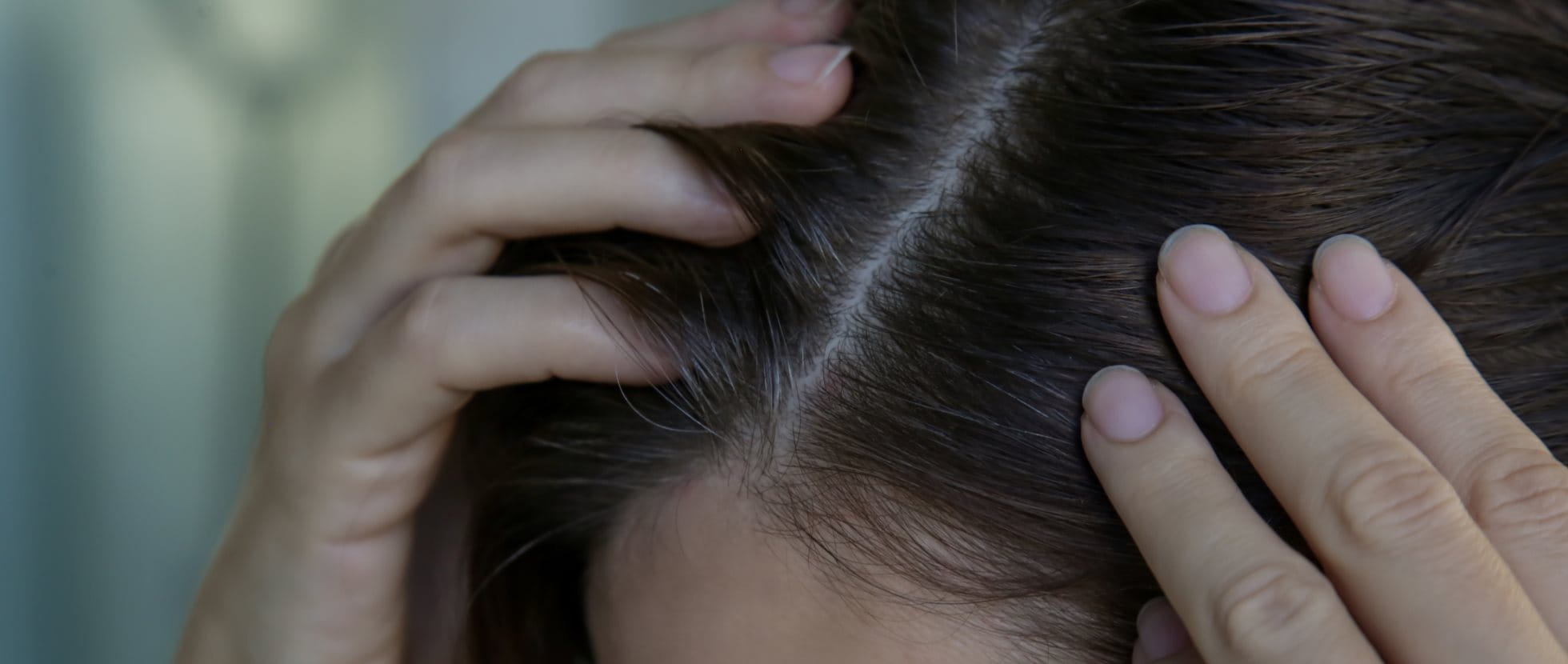 Frau betrachtet ihre Haare im Spiegel