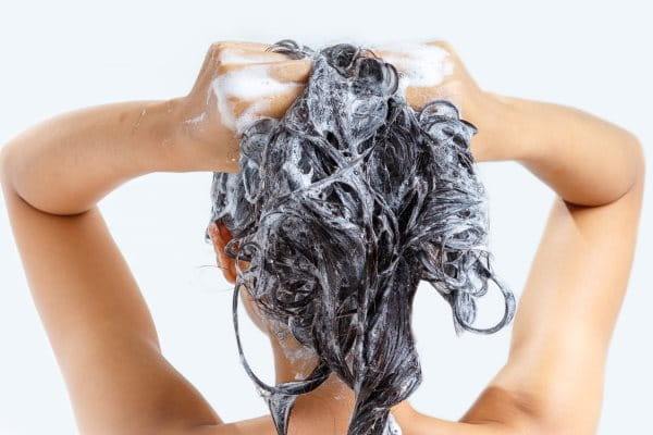 Frau wäscht sich die Haare mit Shampoo