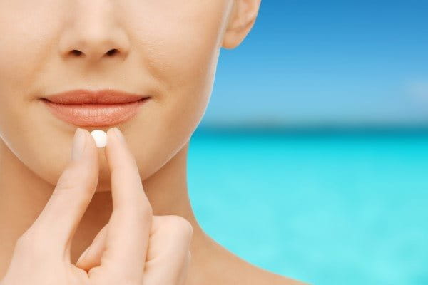 Frau in der Sonne nimmt Antibiotikum ein