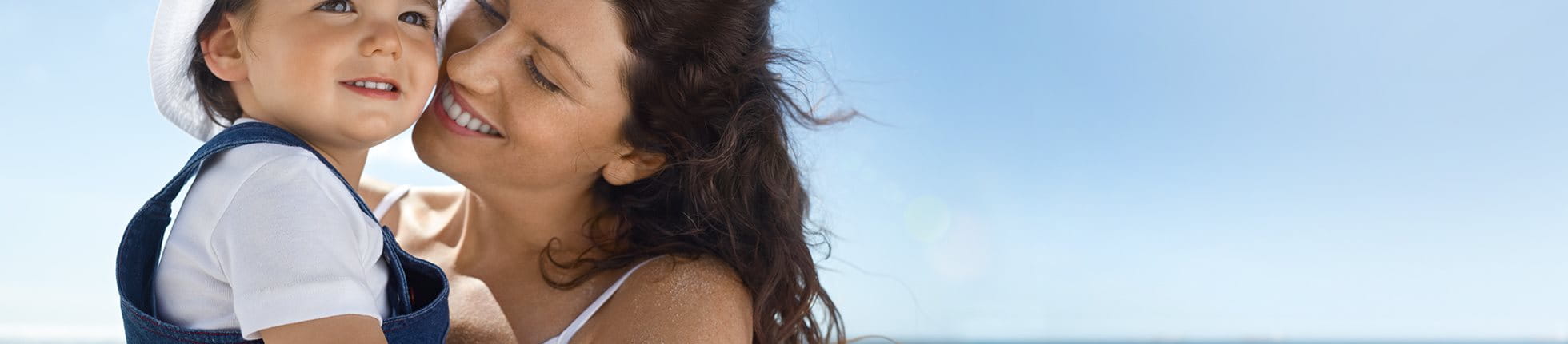 Frau am Strand hält Kind im Arm