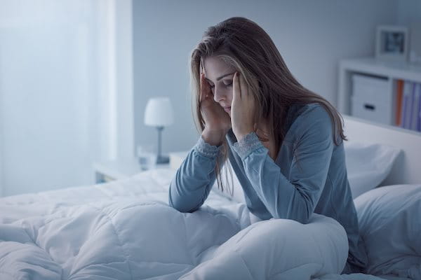 Frau sitzt erschöpft im Bett