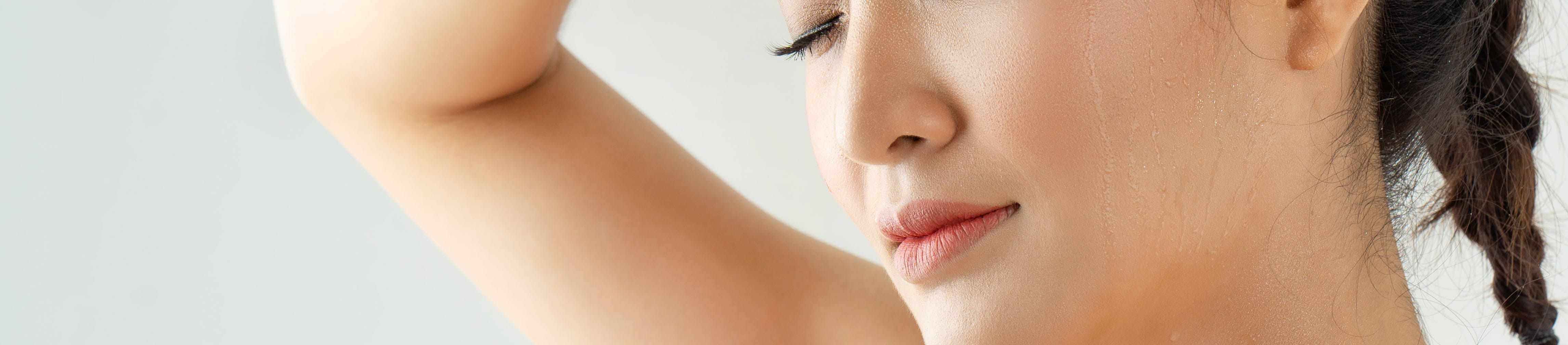 Frau mit geschlossenen Augen wischt sich den Schweiß von der Stirn nach dem Training.