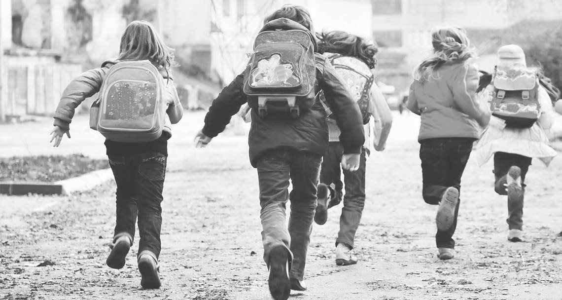 Grupo de niños corriendo hacia el colegio