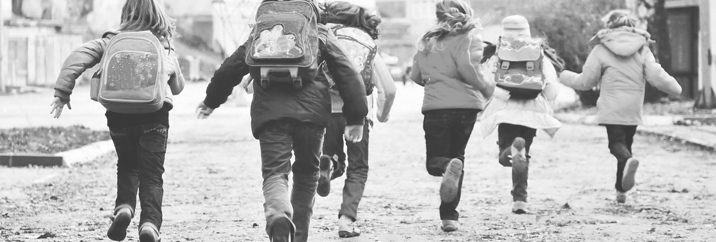 Grupo de niños corriendo hacia el colegio