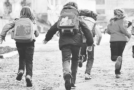 Un grupo de niños corriendo hacia el colegio