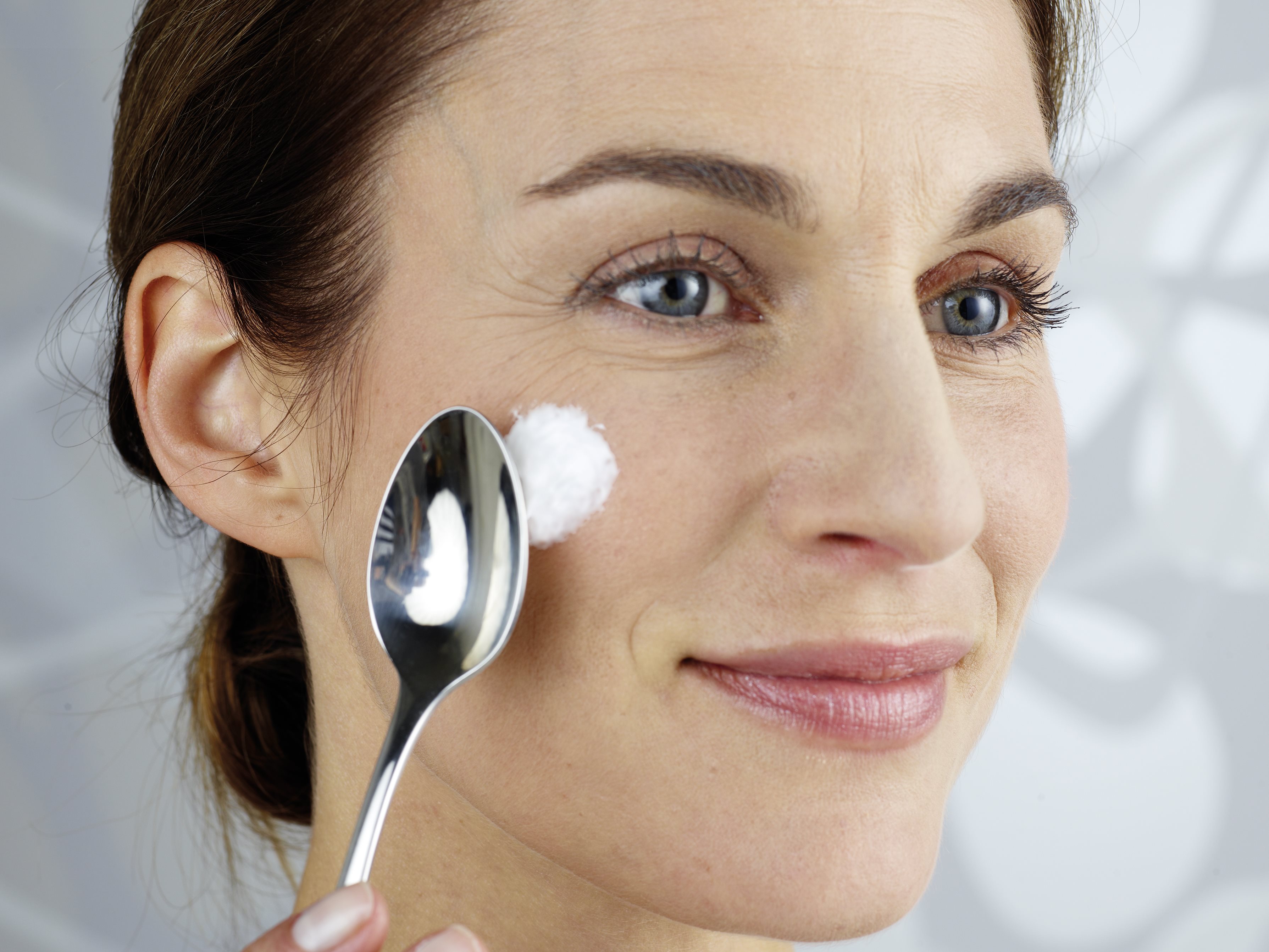 Woman applying creme with a spoon to her face
