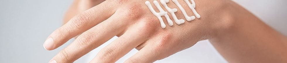 HELP written out on the back of a hand with creme