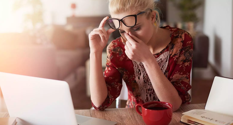 Woman holding her face stressed sitting in front of her laptop