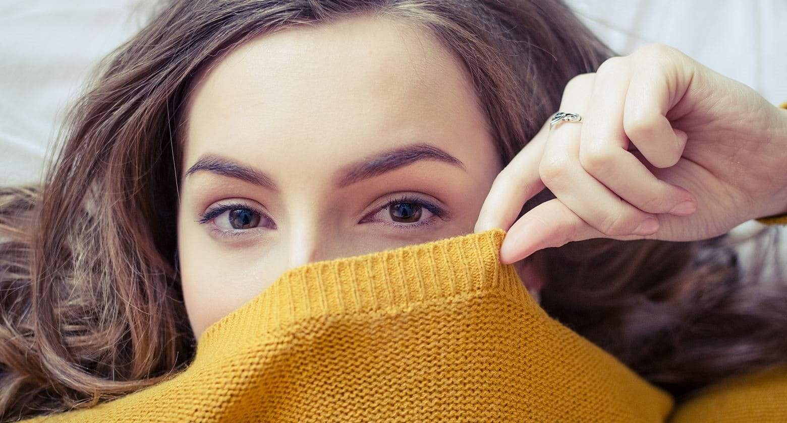 Woman covering the bottom part of her face with a sweater