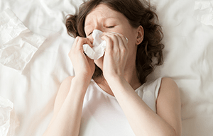 Žena puše nos u krevetu