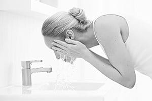 Woman cleansing face