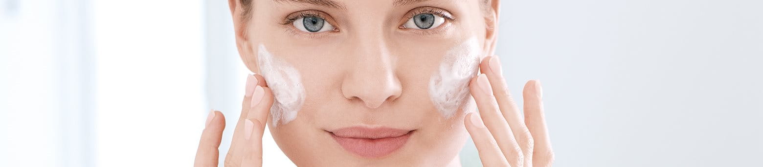 Frau cremt ihre Wangen ein