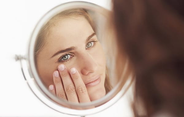 woman applying make-up to acne-prone skin