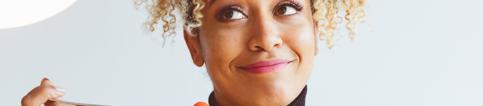 en kvinna som ler medan hon äter en sallad