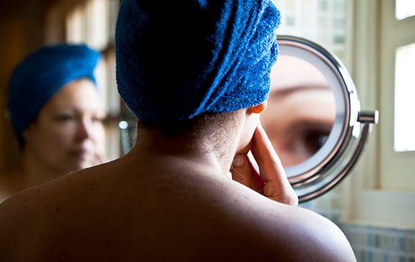 woman looking at acne in mirror