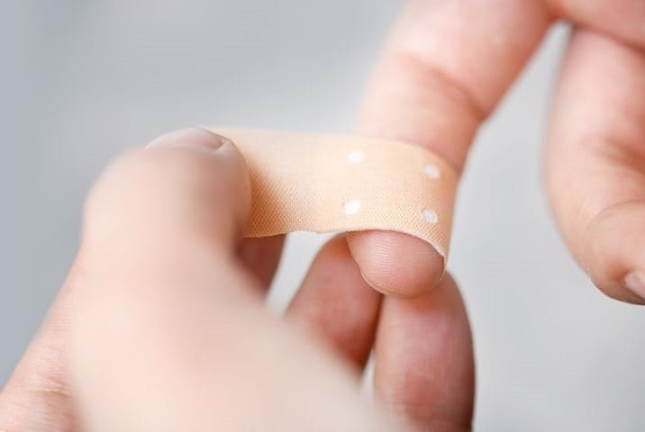 person putting a plaster on their finger