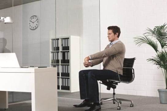 Homme qui s'assoit sur une chaise et étire son poignet