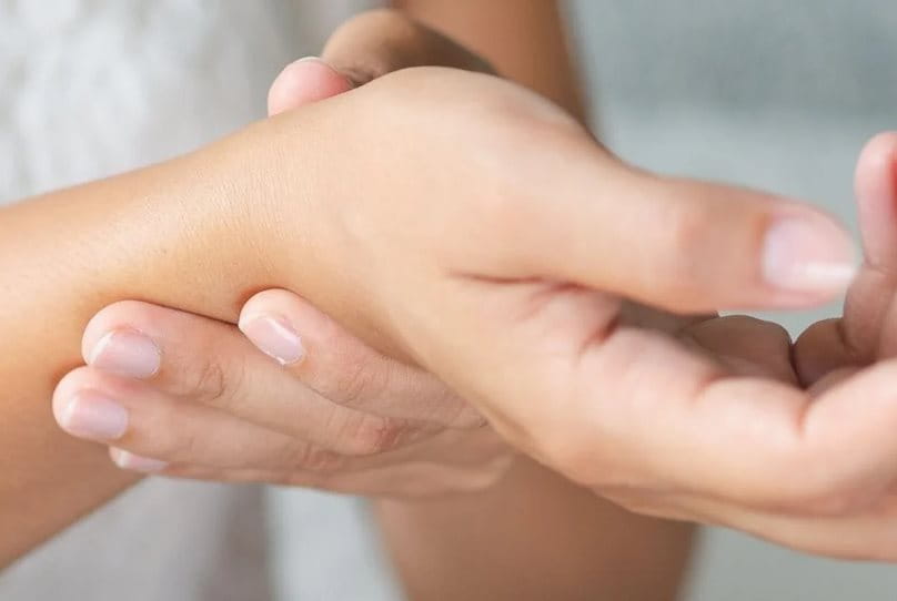 Women holding her wrist with the other hand