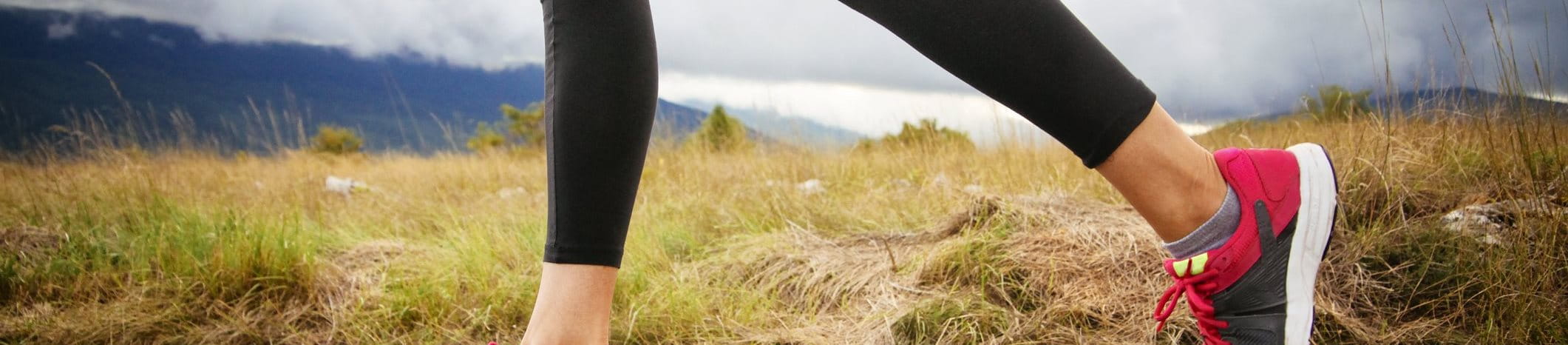 A woman in gym clothes with a Hansaplast Blister Plaster on her heel is getting in her trainers.